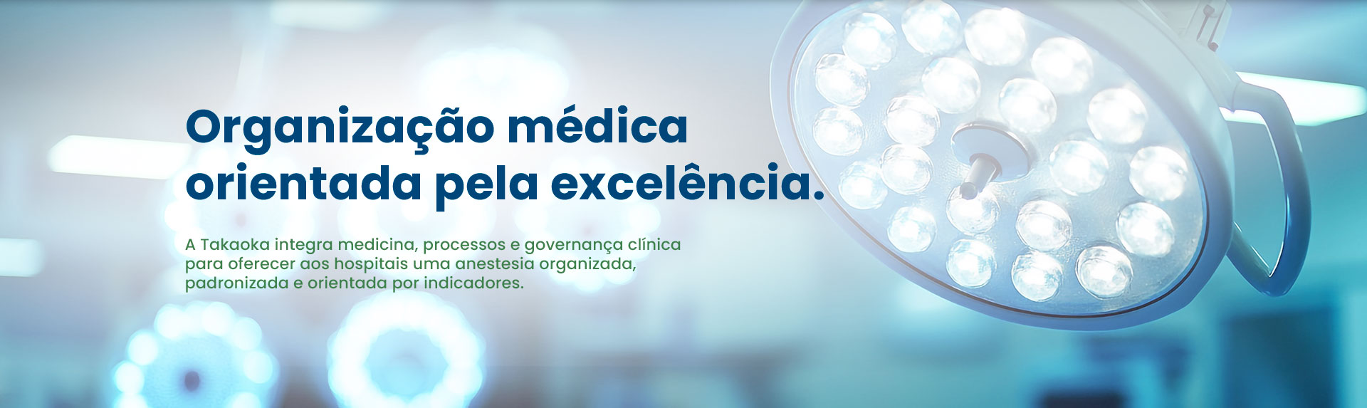Banner institucional da Takaoka Anestesia com a frase 'Organização médica orientada pela excelência'. Ao fundo um sistema de iluminação no Centro cirúrgico do hospital da Takaoka Anestesia
